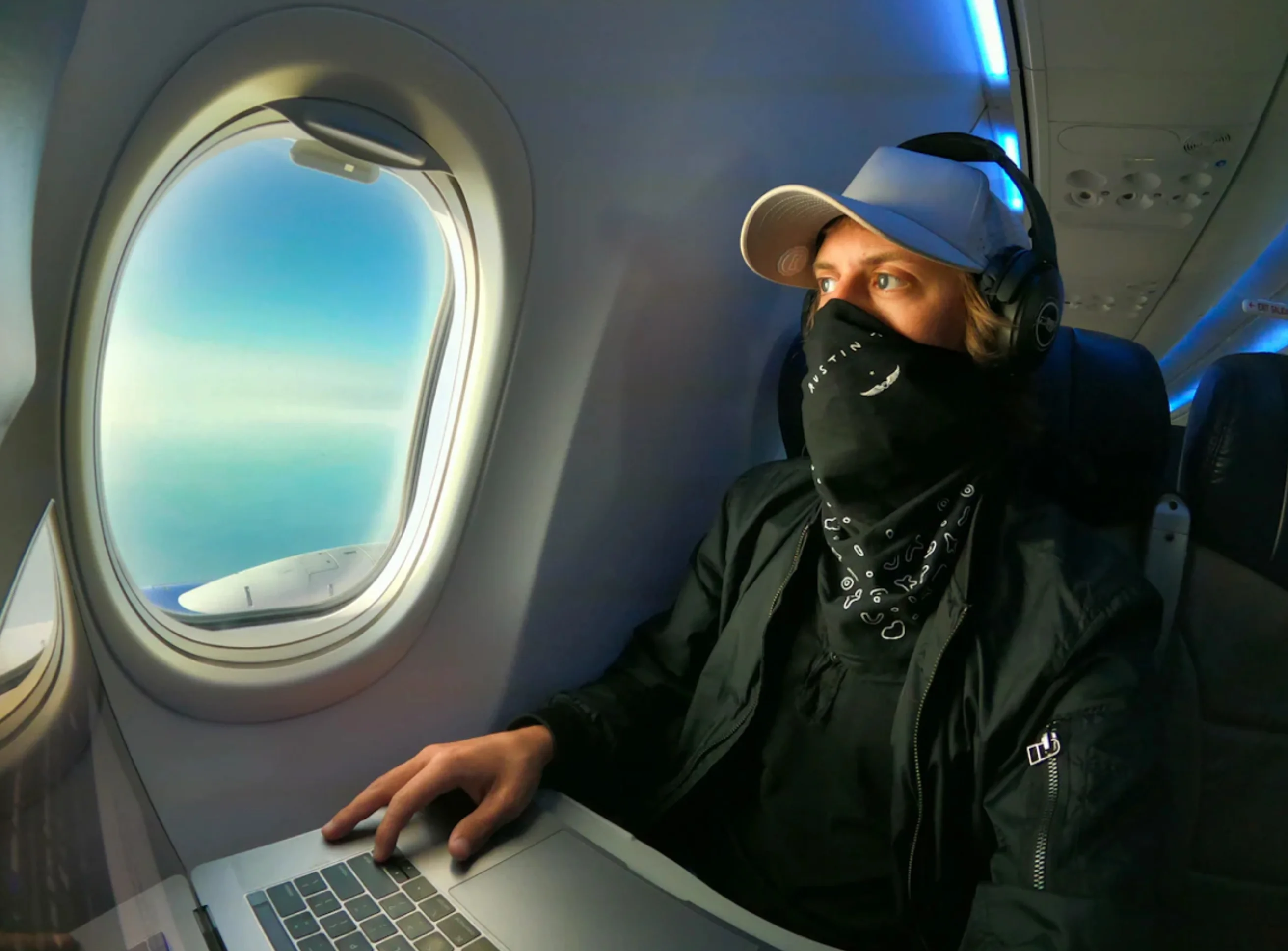 Remote worker on an airplane with a laptop and mask.