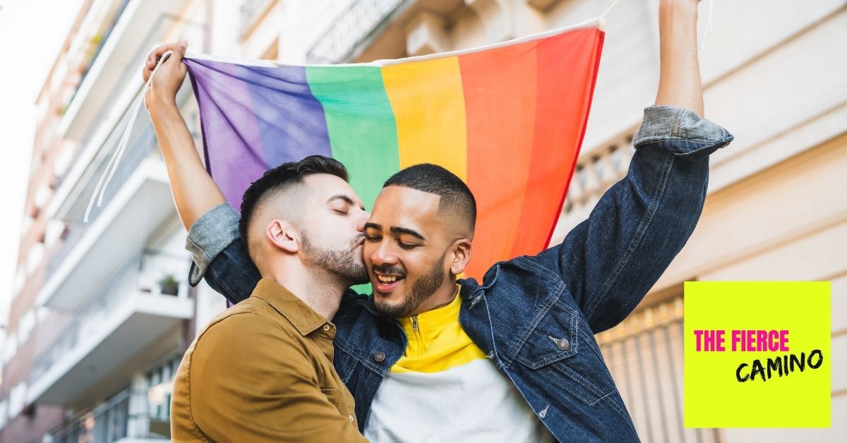 Queer Digital Nomads kissing and holding up a rainbow flag